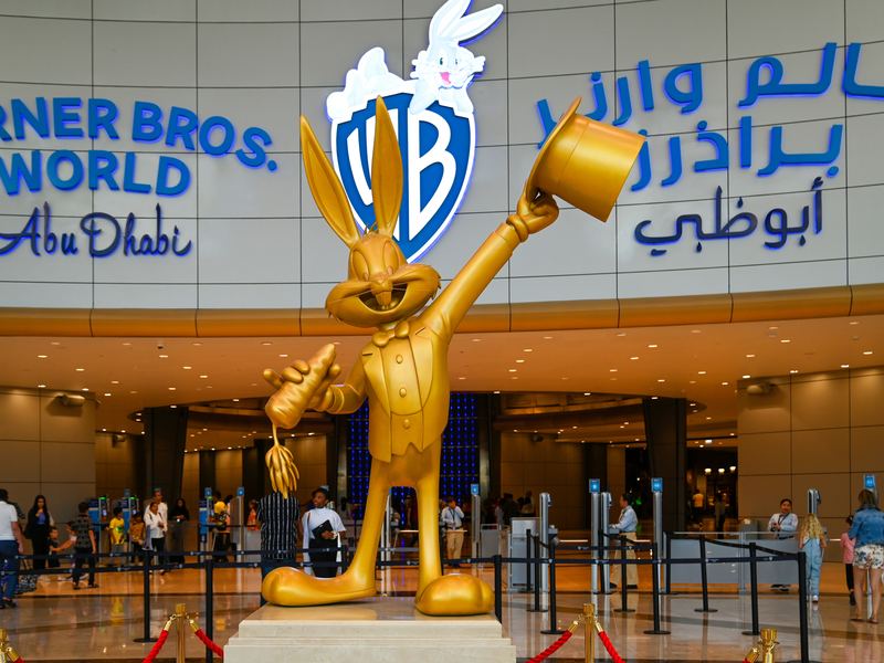 Warner Bros. World Abu Dhabi entrance with the WB shield logo and a Bugs Bunny statue